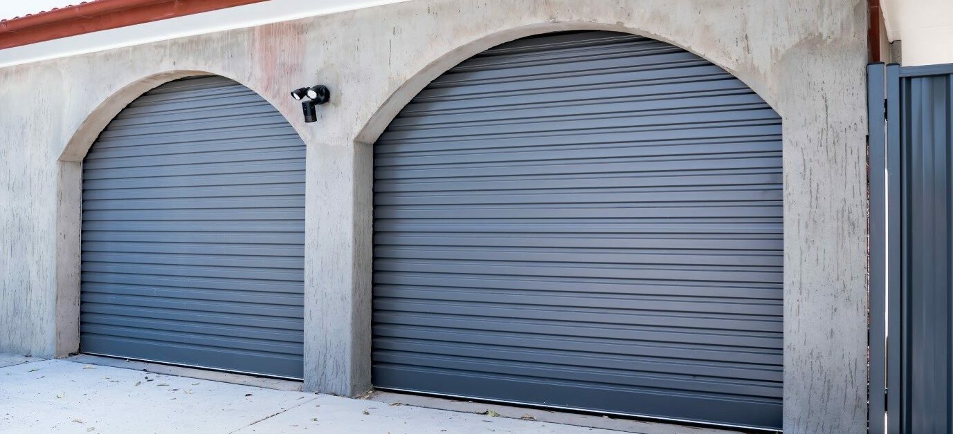 Two charcoal B&D roller garage doors set within rendered arches