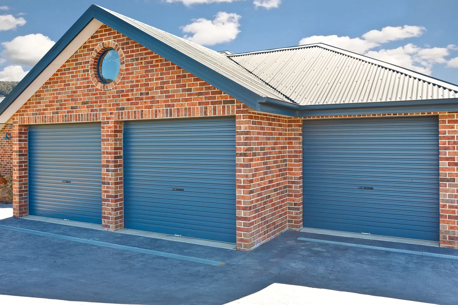 Three blue B&D Rollmasta roller garage doors on a brick garage