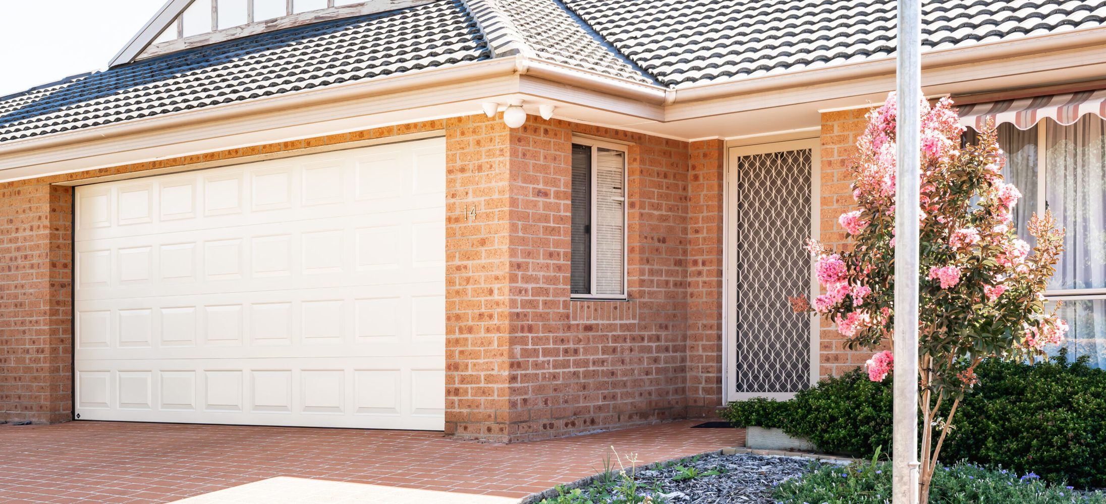 Classic Cream B&D Panelift sectional garage door on a brick home